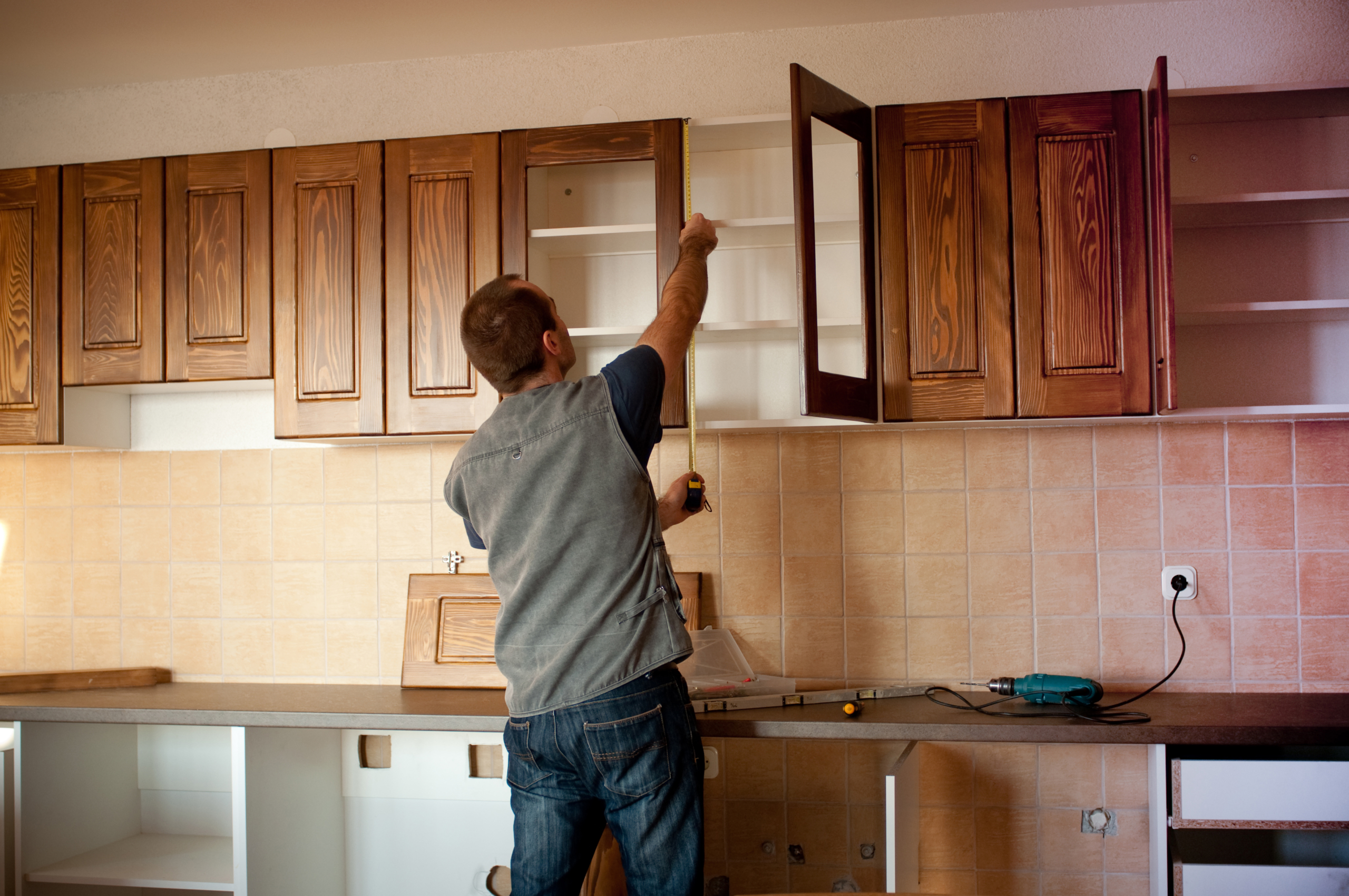 Man constructing cabinet units in new kitchen Cabinet Corner